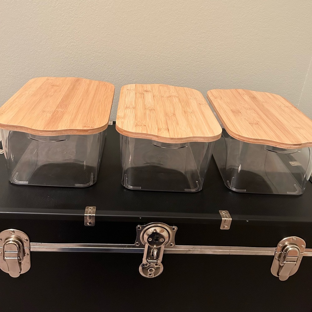 A set of three storage containers with wood lids